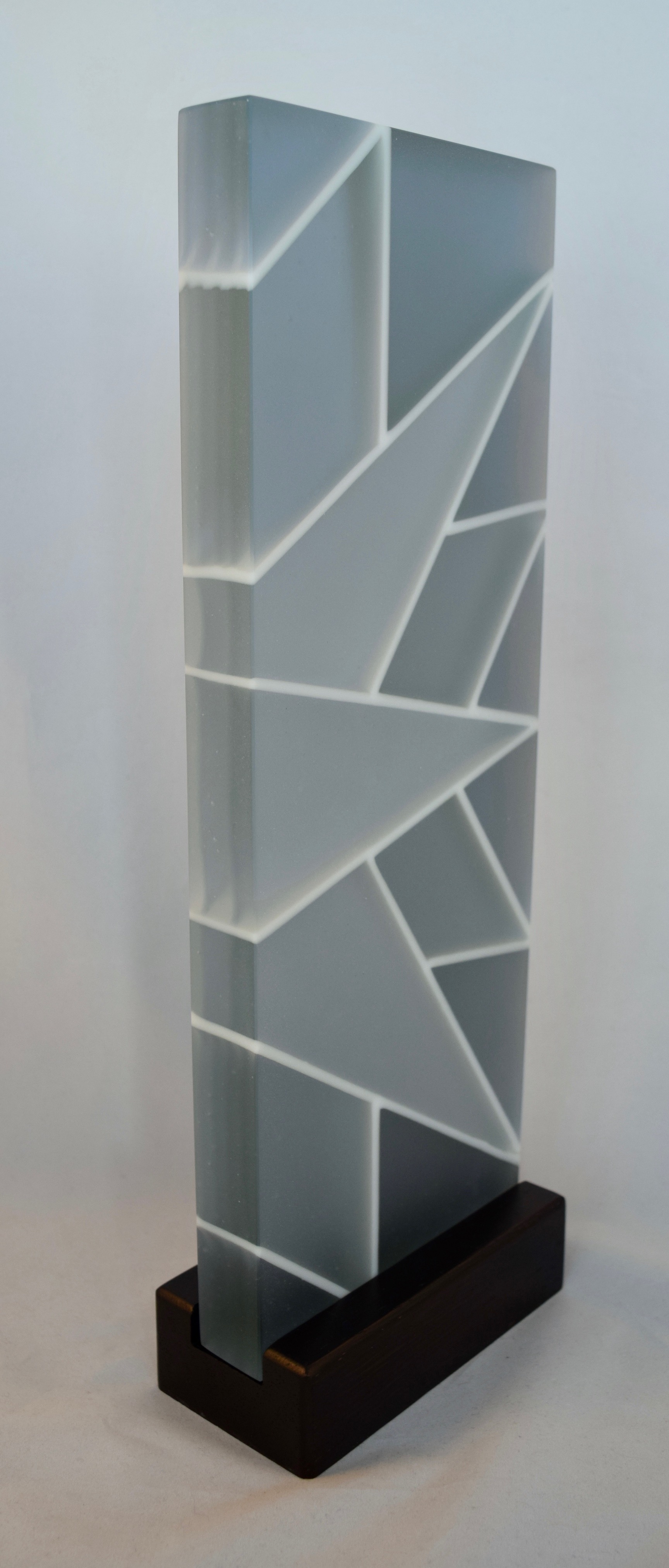 Quiet Radiance - Kiln-formed glass sculpture created from various shades of blue and white glass. Sculpture changes to shades of vivid blue-green under LED lighting. Hand-sanded to a translucent finish. Glass with wood stand measures 15.25 x 5.5 x 2.75". Available for purchase through Chasen Galleries in Richmond, Virginia.