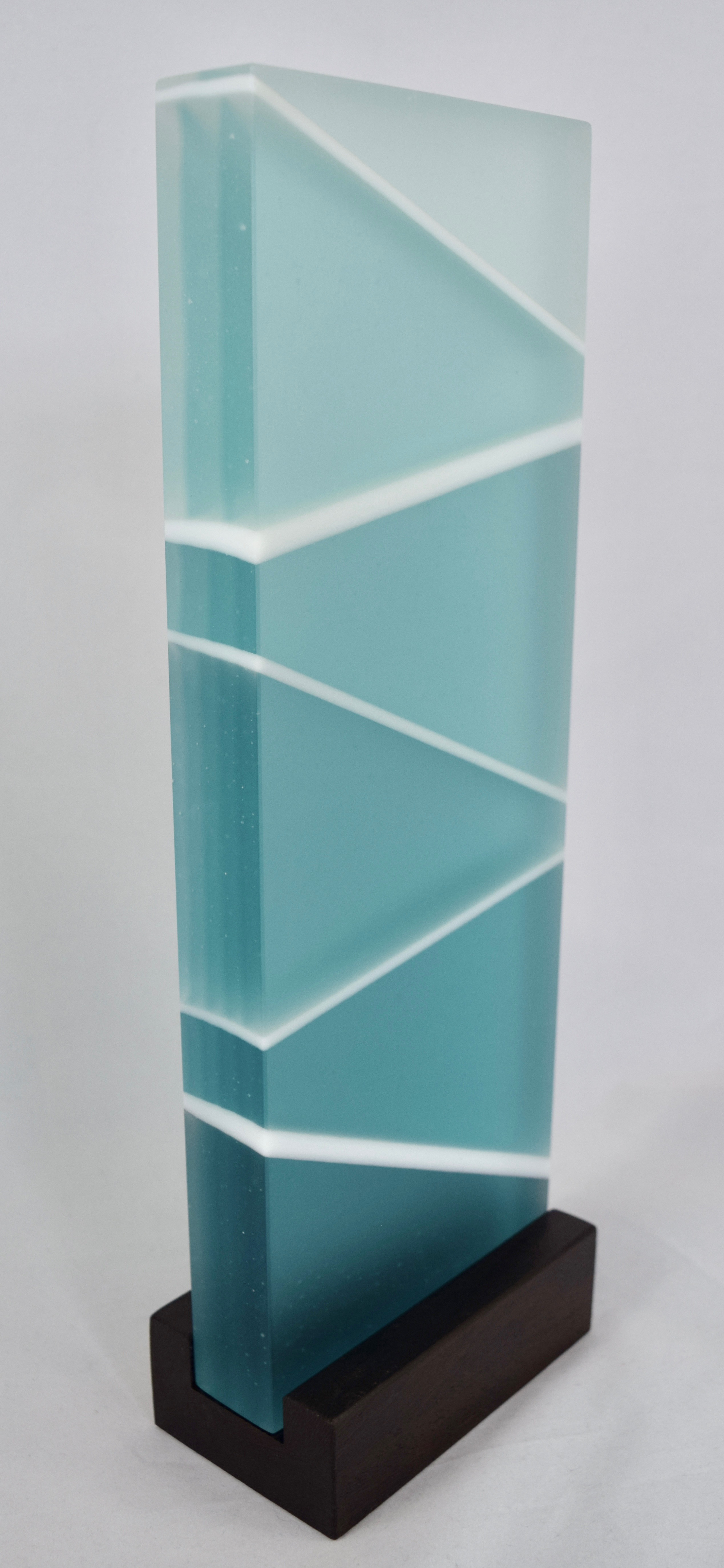 Coastal - Kiln-formed glass sculpture created from various shades of aqua and white glass. Hand-sanded to a translucent finish. Glass with wood stand measures 13.875 x 4.75 x 2.75". Available for purchase through Chasen Galleries in Sarasota, Florida.