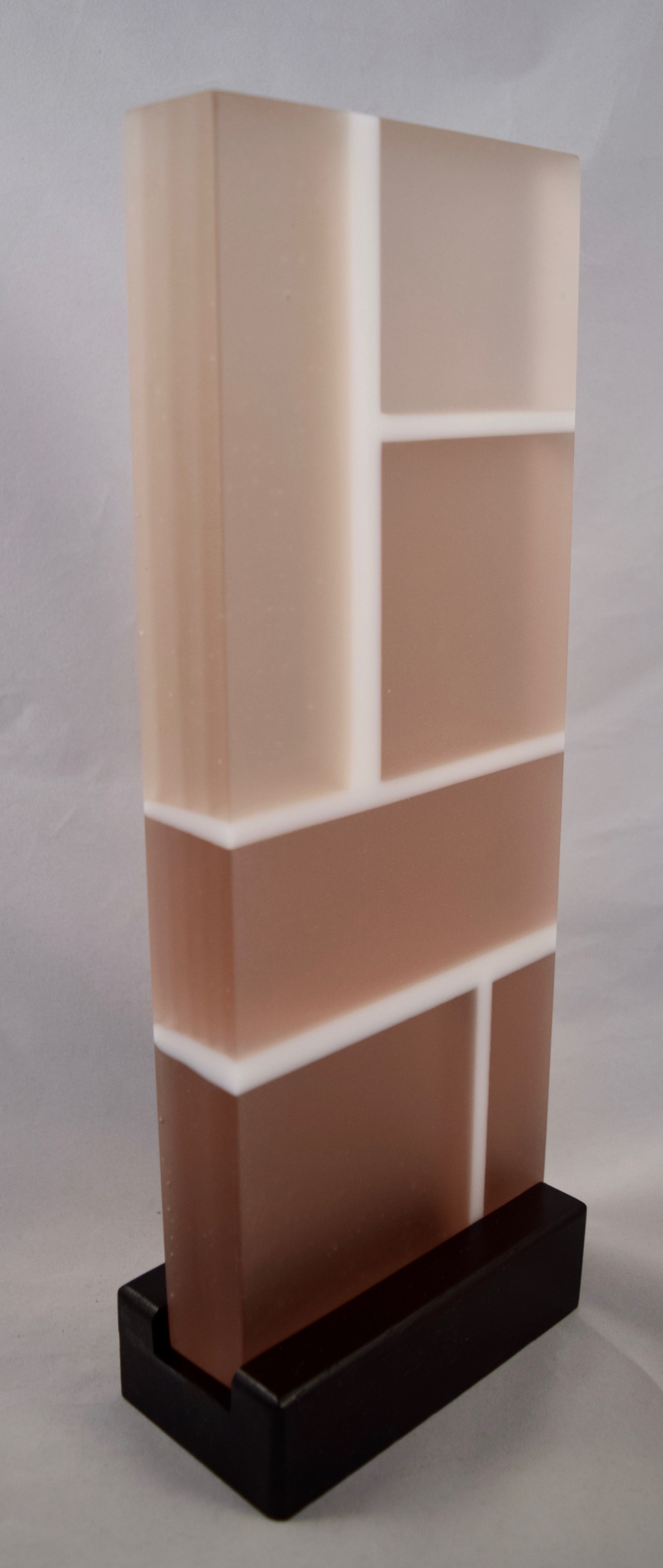 Cornerstone - Kiln-formed glass sculpture created from various shades of rhubarb and white glass. Sculpture changes to shades of olive green under LED lighting. Hand-sanded to a translucent finish. Glass with wood stand measures 5.25"w x 13.5"h x 2.75"d. Sculpture is available for sale.